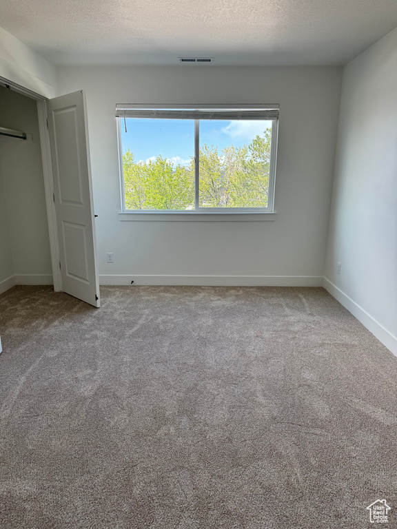 Unfurnished bedroom with carpet flooring, baseboards, and a textured ceiling