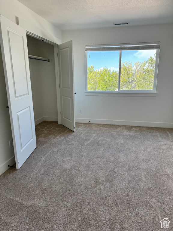 Unfurnished bedroom with carpet flooring, baseboards, and a textured ceiling