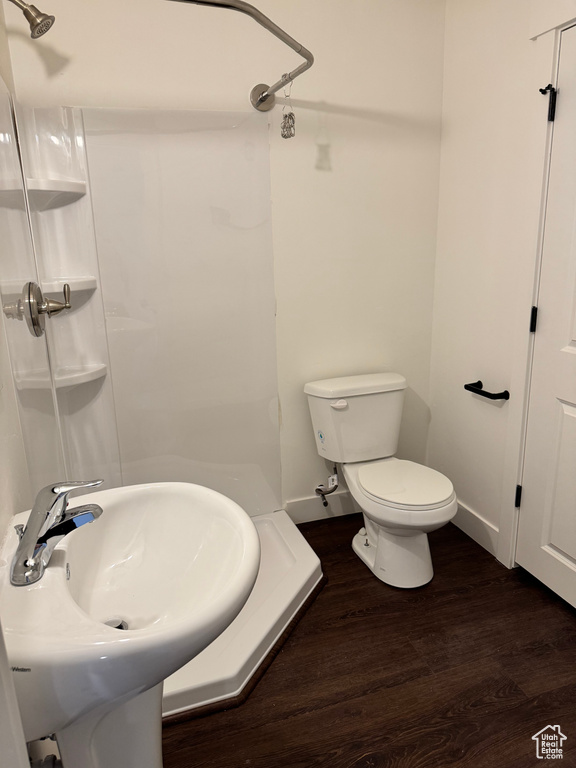 Bathroom featuring a shower, wood finished floors, toilet, and a sink