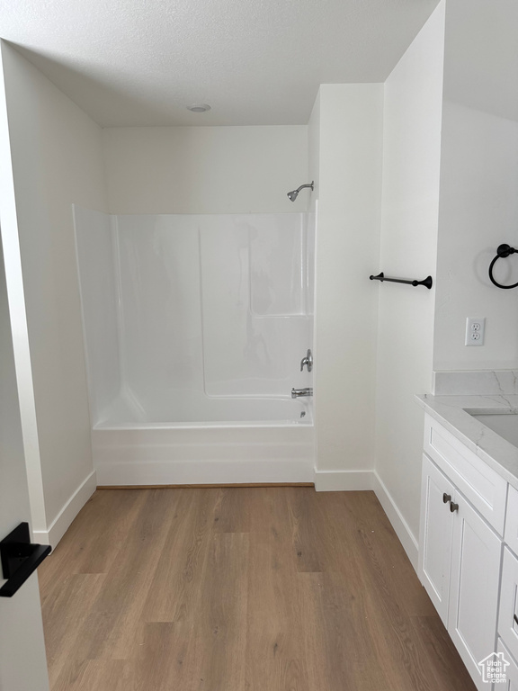 Full bathroom with wood finished floors, washtub / shower combination, baseboards, and vanity