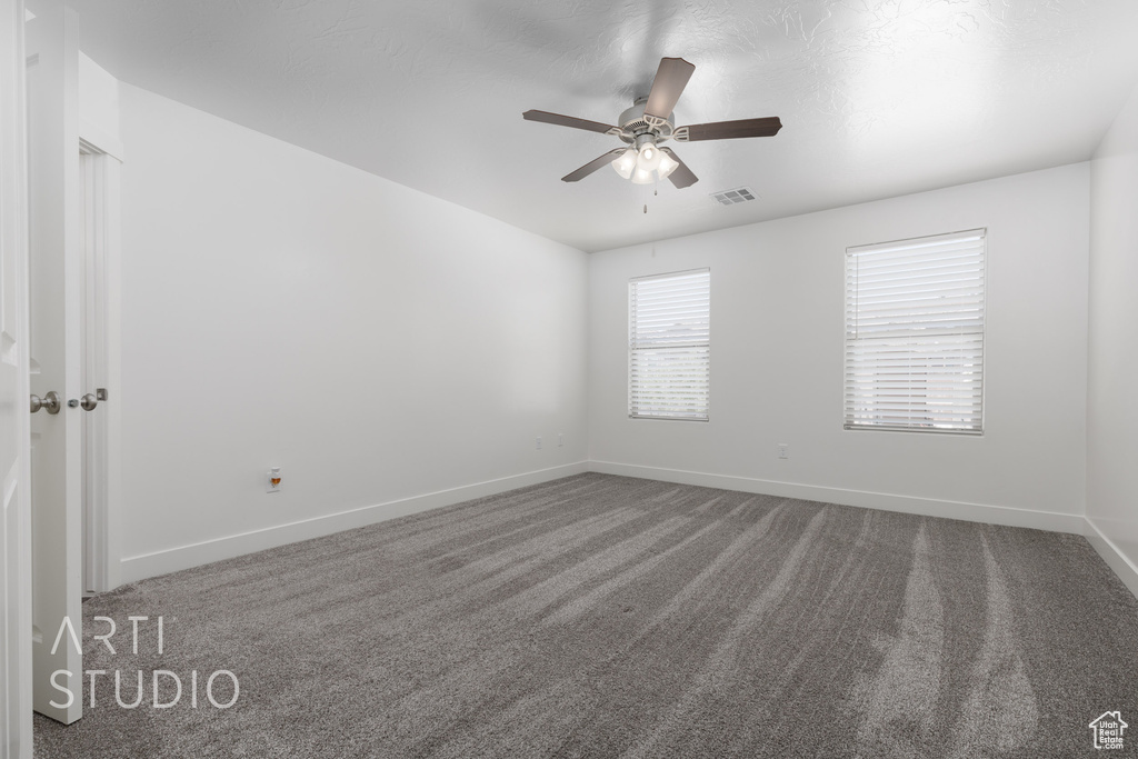 Carpeted empty room with a ceiling fan and baseboards