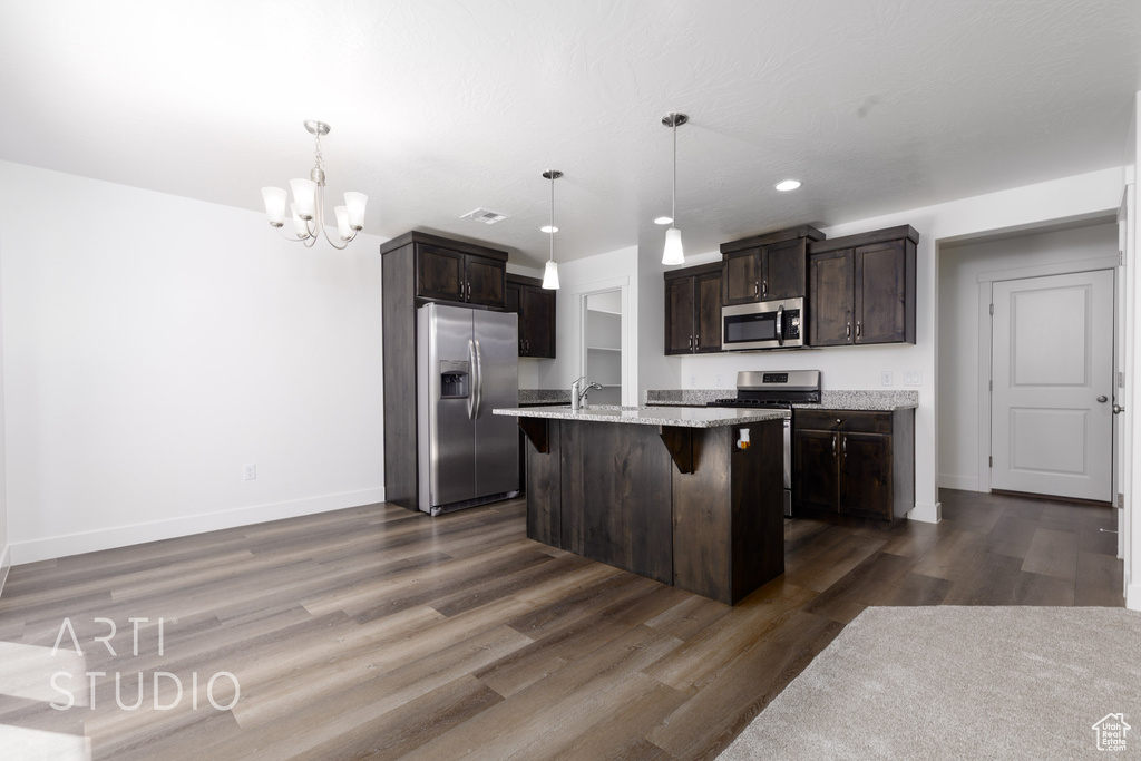 Kitchen featuring appliances with stainless steel finishes, dark brown cabinets, a breakfast bar, a chandelier, and recessed lighting