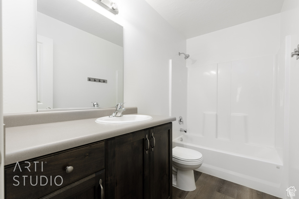 Bathroom featuring toilet, vanity, wood finished floors, and bathtub / shower combination