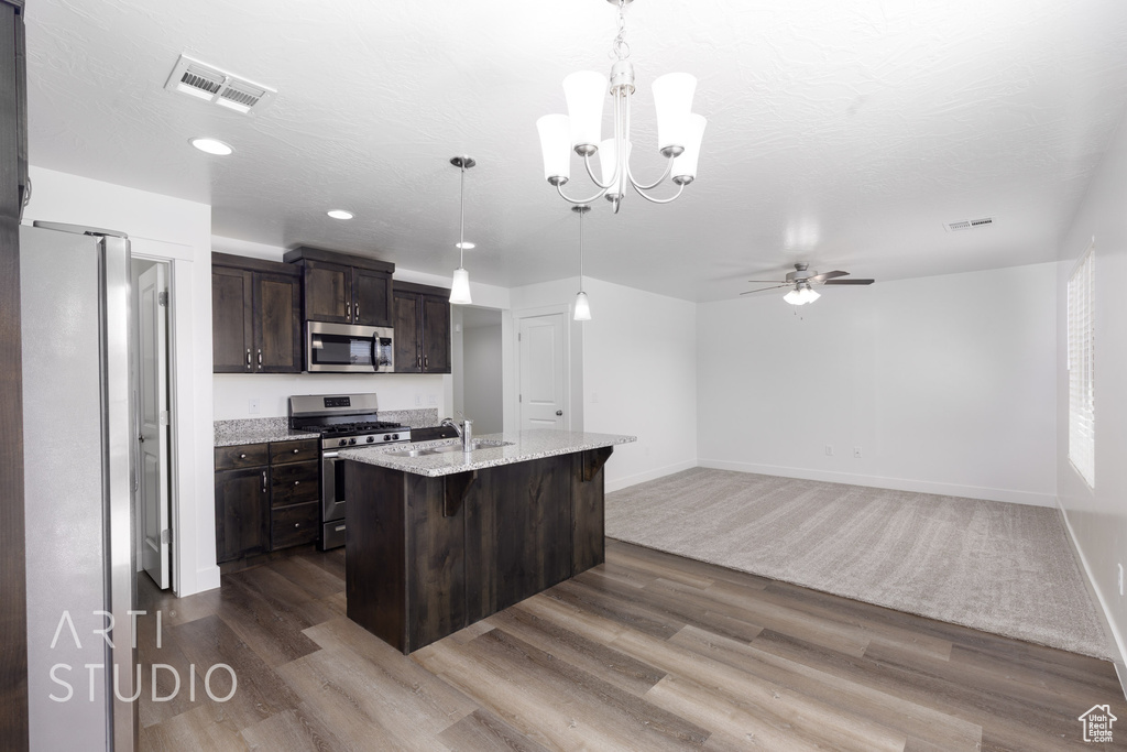 Kitchen featuring stainless steel appliances, dark brown cabinets, dark wood finished floors, a chandelier, and recessed lighting