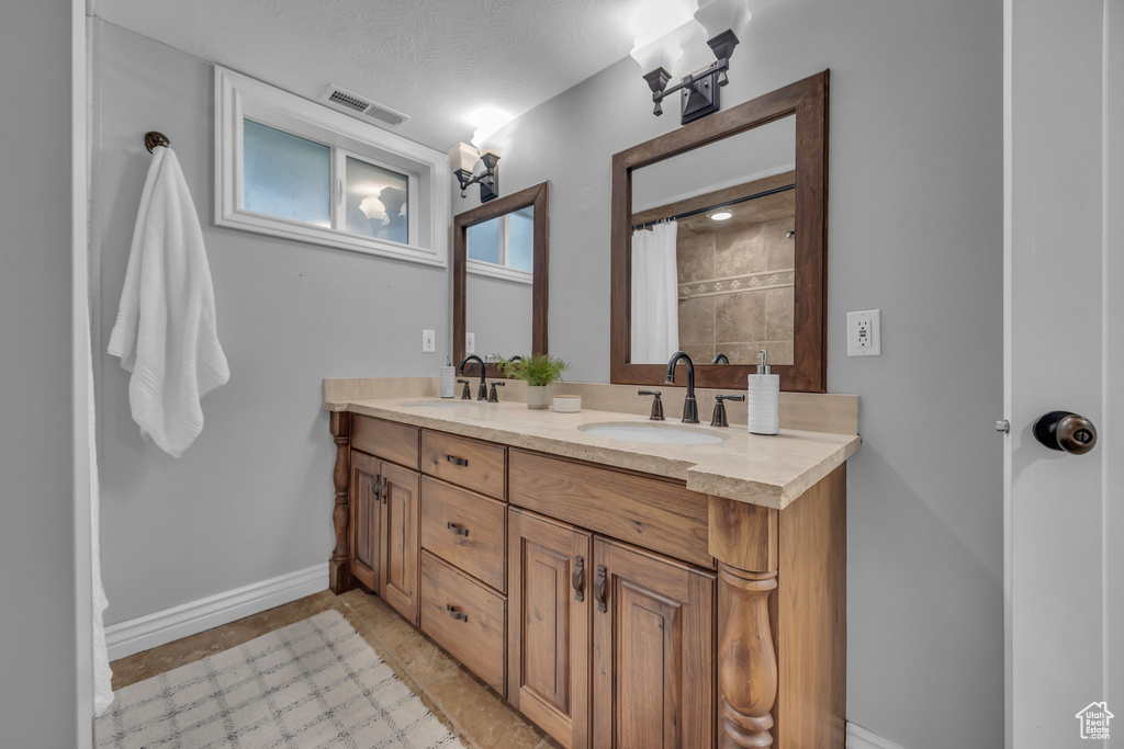 Full bath featuring baseboards and double vanity