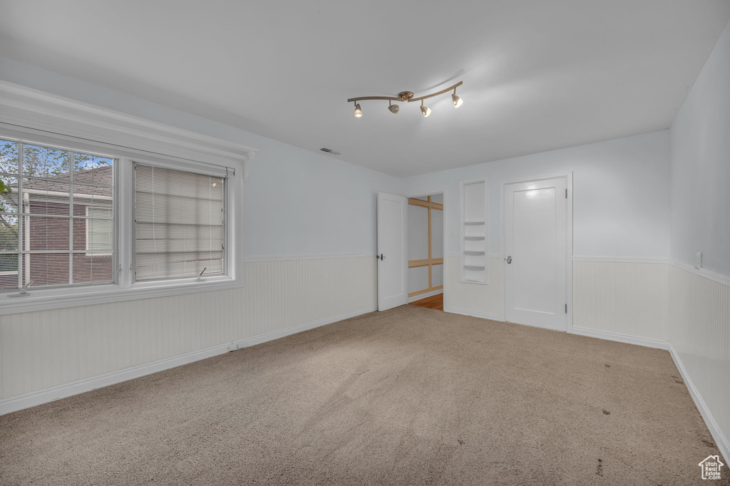 Carpeted spare room featuring wainscoting
