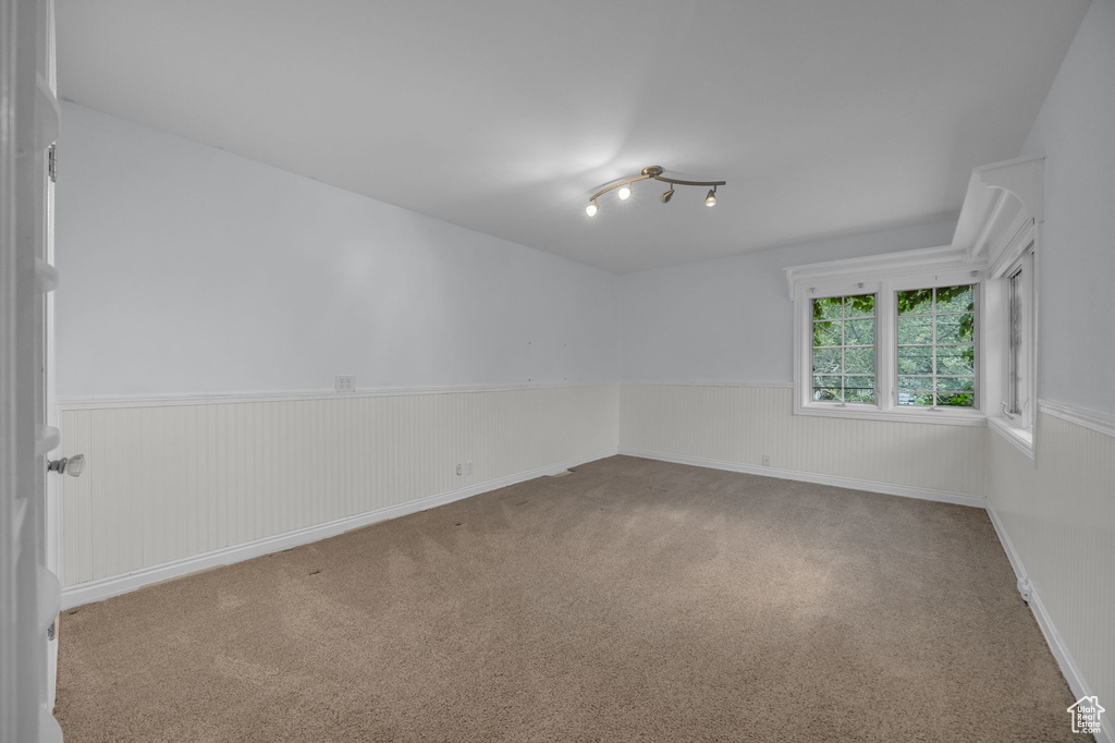 Carpeted spare room featuring wainscoting