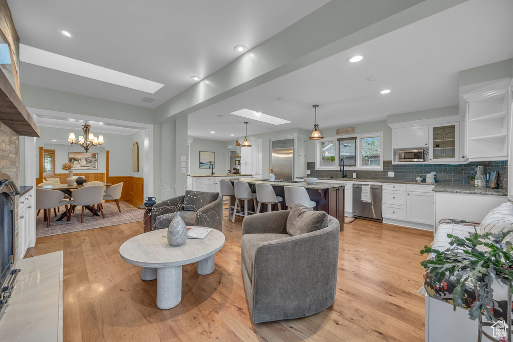 Living area featuring a chandelier, light wood finished floors, a skylight, and recessed lighting