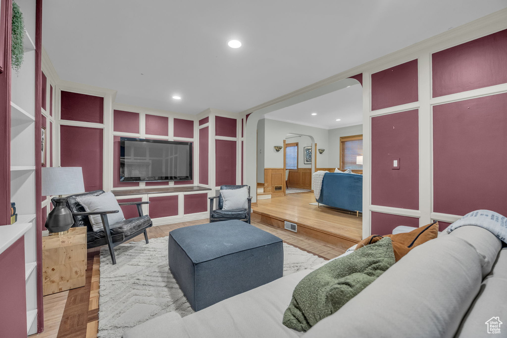 Living area featuring arched walkways, recessed lighting, and crown molding