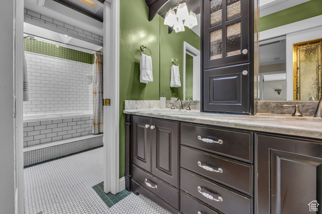 Bathroom with tile patterned floors, double vanity, and tiled shower / bath combo