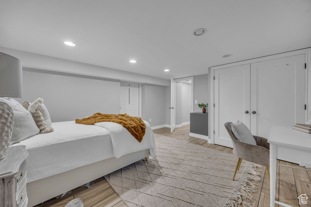 Bedroom with light wood-style floors, recessed lighting, baseboards, and a closet