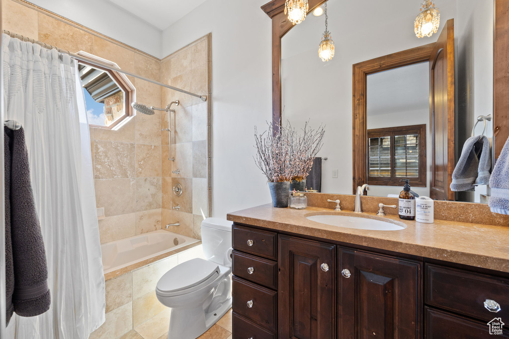 Bathroom with vanity, toilet, tiled shower / bath, and a healthy amount of sunlight