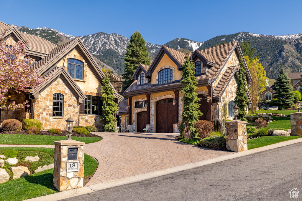 View of front of property featuring stone siding, a mountain view, stucco siding, and curved driveway