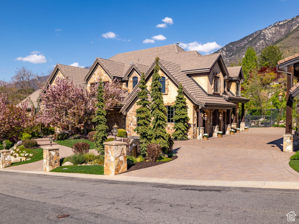 View of front of property featuring stone siding, a mountain view, stucco siding, and a tiled roof