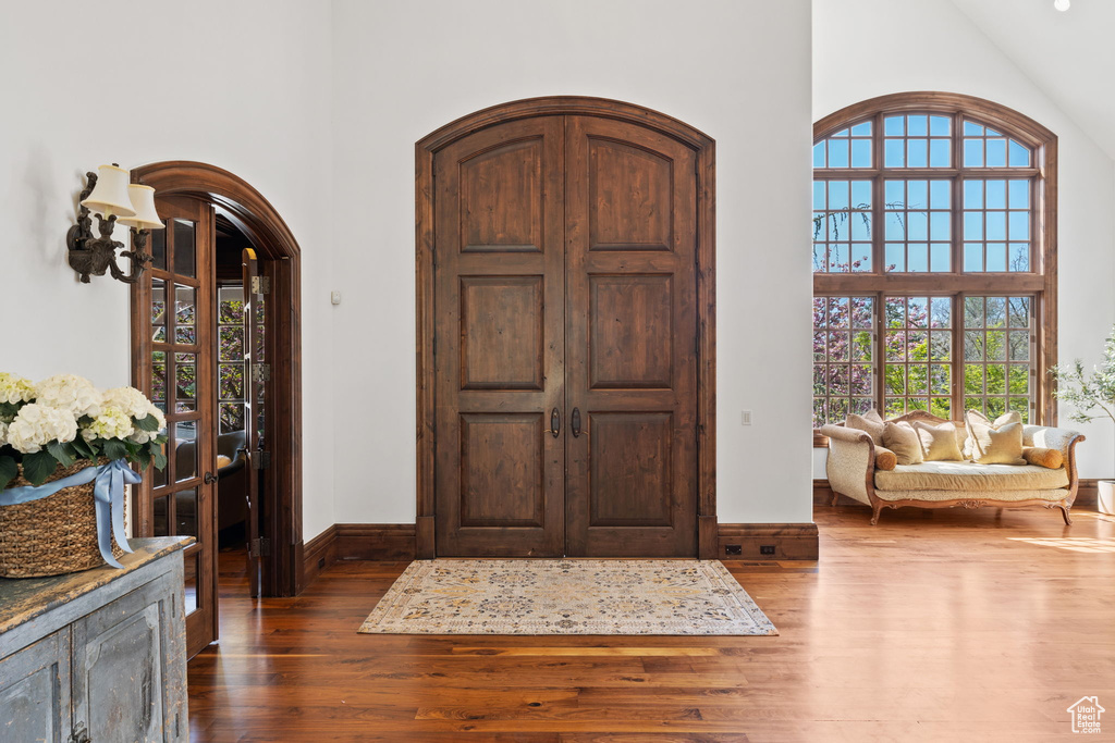Entryway featuring dark wood-style flooring, a high ceiling, baseboards, and arched walkways