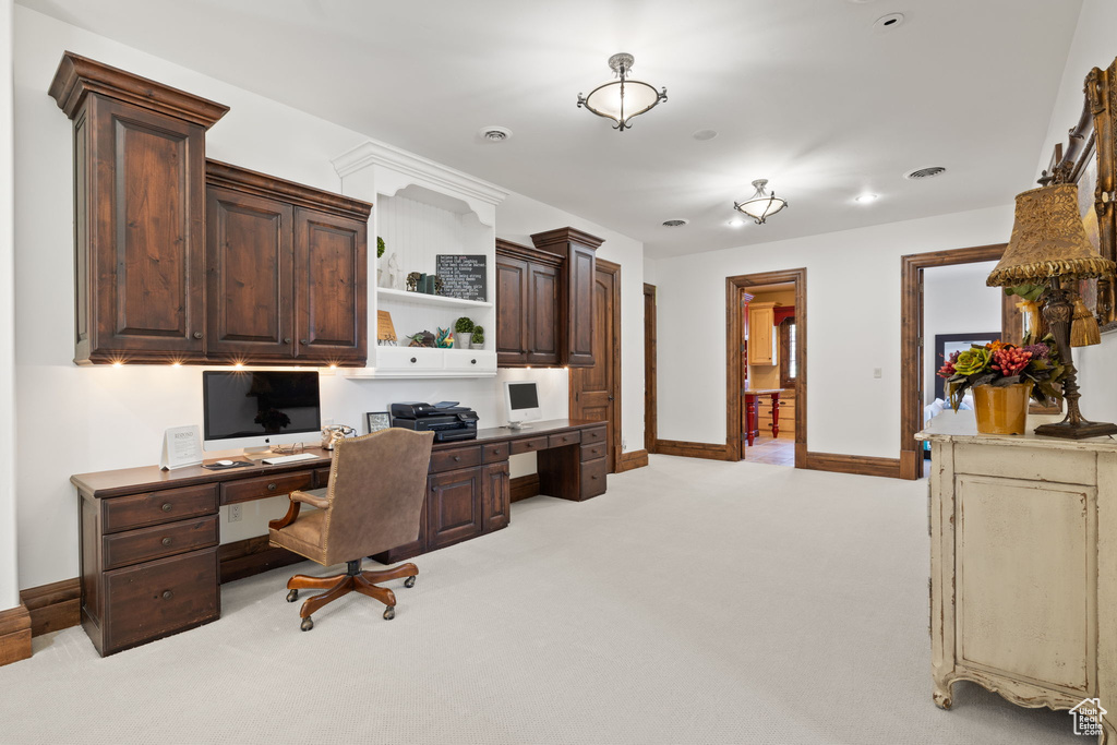 Office featuring built in desk, light carpet, and baseboards