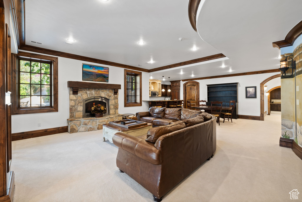 Living area featuring light colored carpet, crown molding, arched walkways, and baseboards