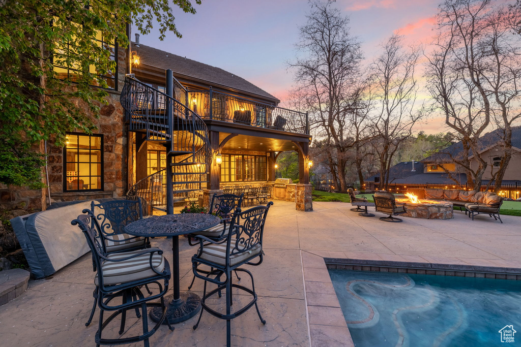 View of patio featuring a balcony, an outdoor pool, outdoor dry bar, stairway, and a fire pit