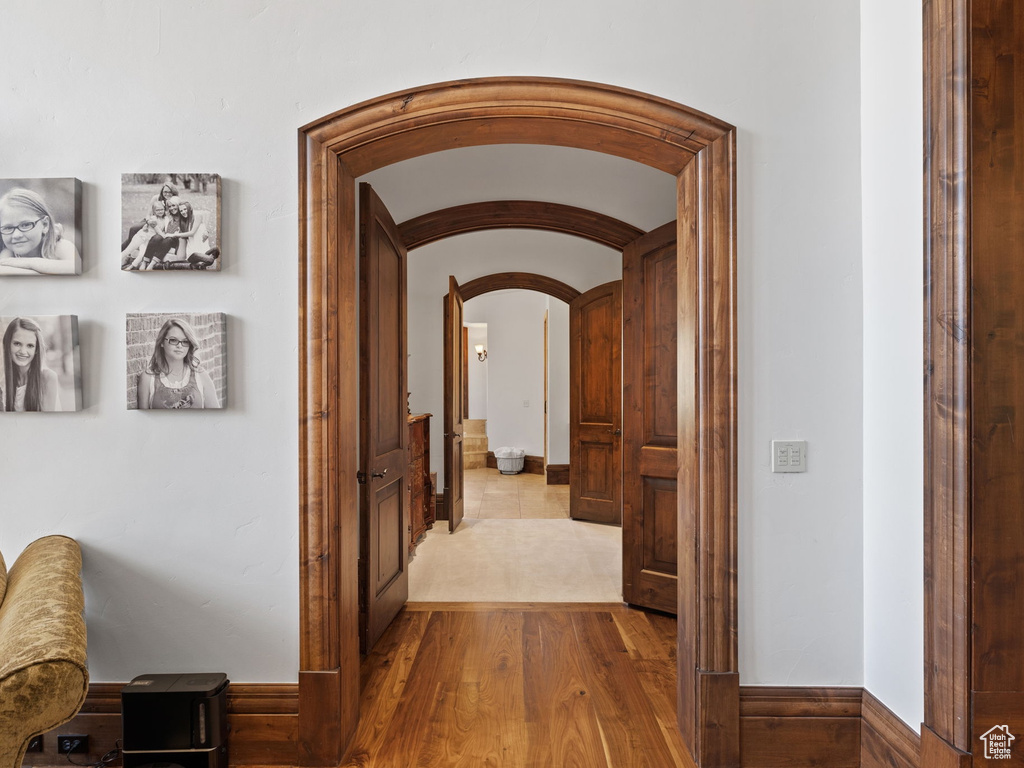 Hall featuring arched walkways and wood finished floors