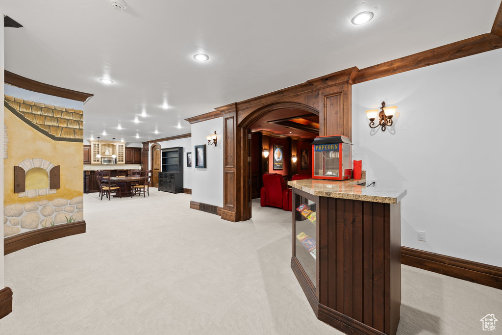Interior space with baseboards, arched walkways, bar area, light carpet, and recessed lighting