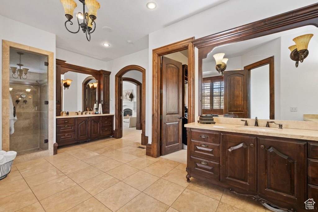 Full bath featuring tile patterned flooring, a shower stall, two vanities, and a sink