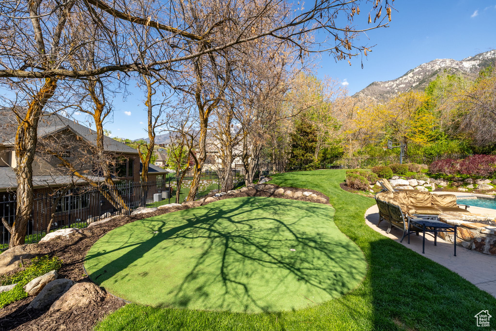 View of yard featuring a patio area, a fenced in pool, a mountain view, and fence