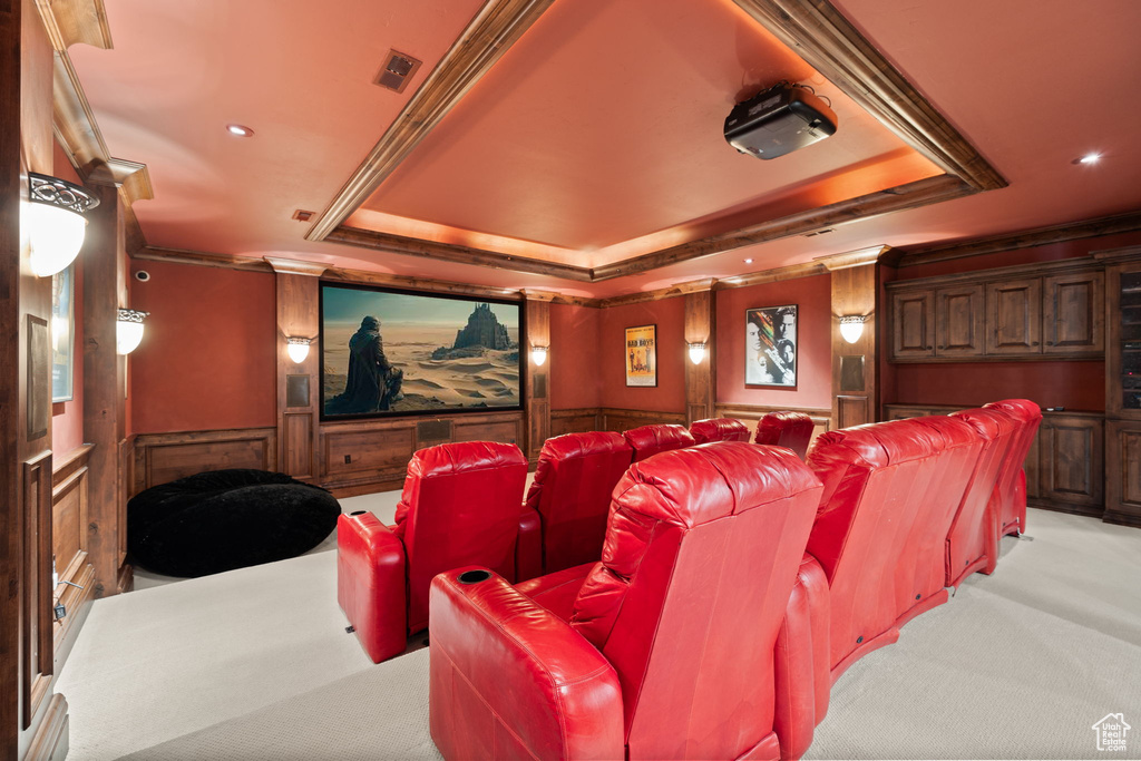 Home theater room featuring a wainscoted wall, light colored carpet, ornamental molding, recessed lighting, and a raised ceiling