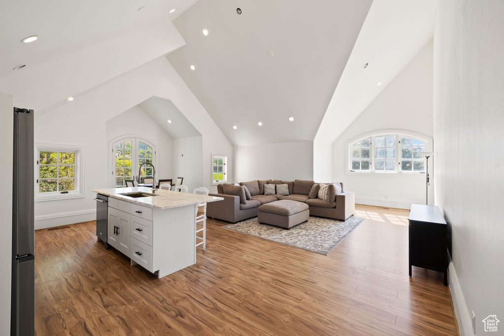 Living room featuring a wealth of natural light, wood finished floors, and high vaulted ceiling