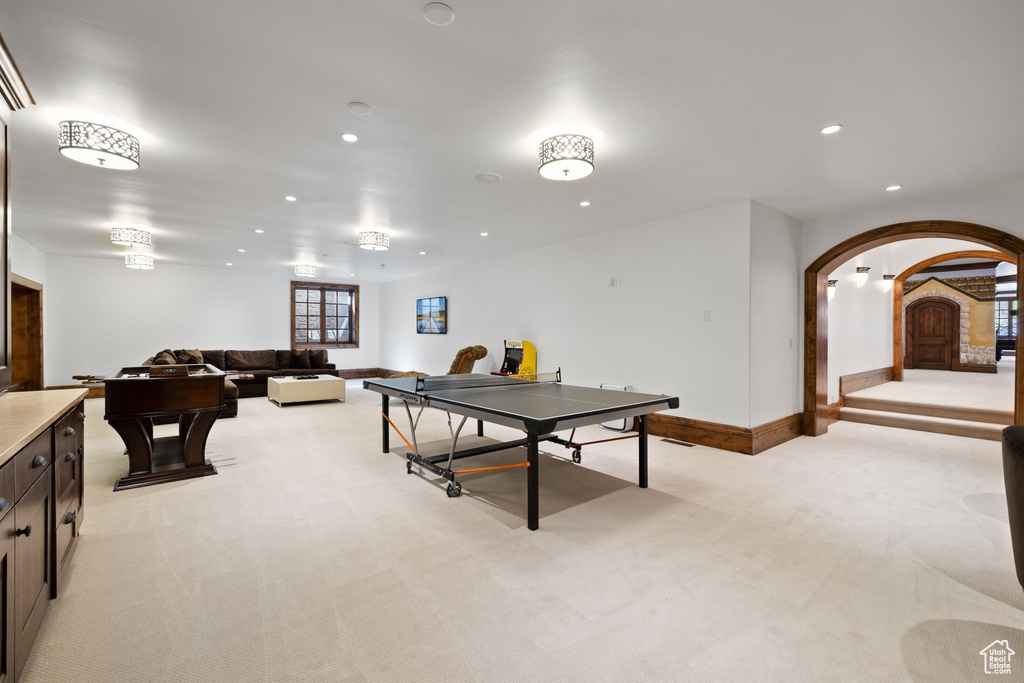 Recreation room with light colored carpet, arched walkways, baseboards, and recessed lighting