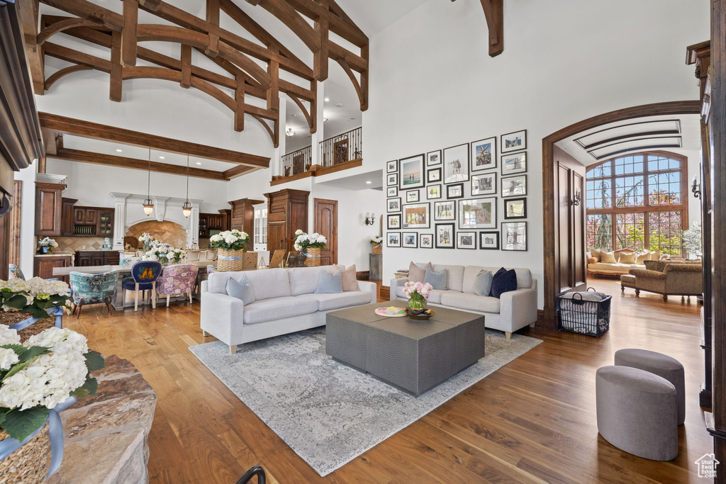 Living room with recessed lighting, high vaulted ceiling, wood finished floors, arched walkways, and beamed ceiling