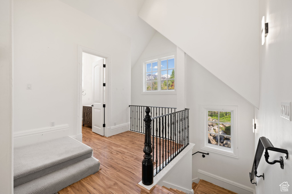 Stairway with wood finished floors, baseboards, and lofted ceiling