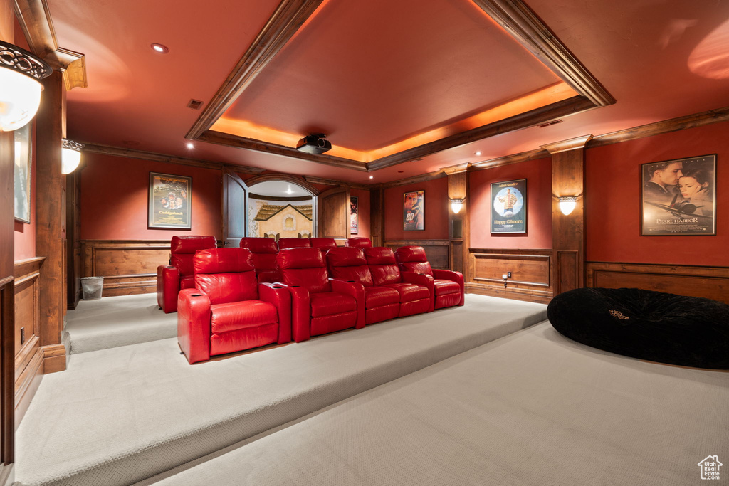 Carpeted home theater room featuring recessed lighting, a tray ceiling, crown molding, and a wainscoted wall