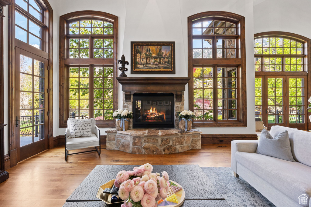 Living room featuring a fireplace, a high ceiling, a healthy amount of sunlight, and wood finished floors