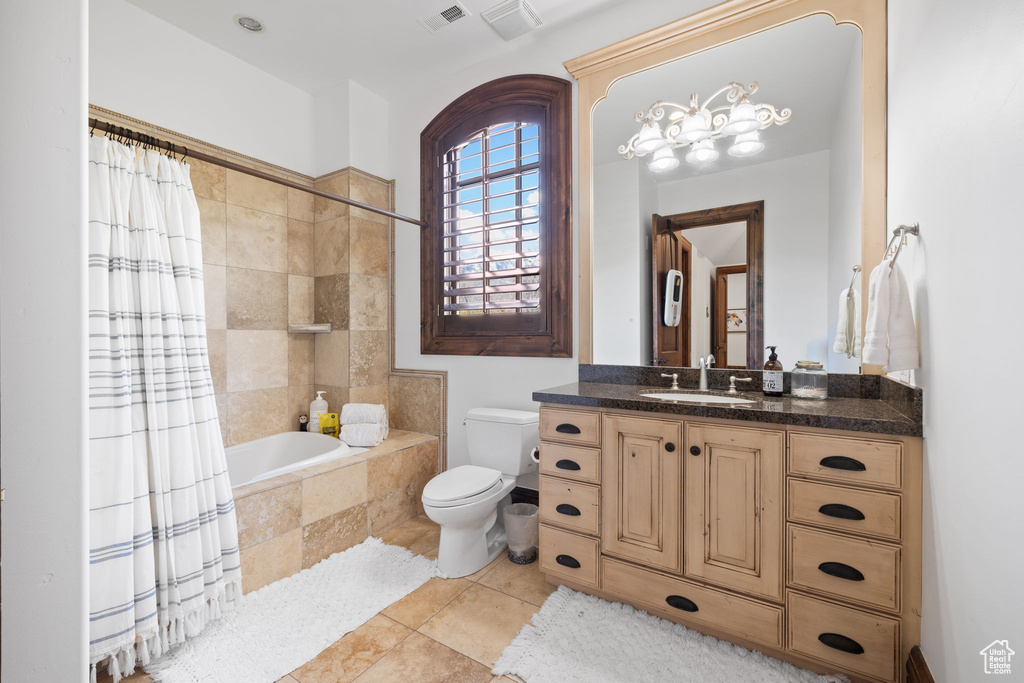 Full bath featuring toilet, tiled shower / bath, vanity, and visible vents