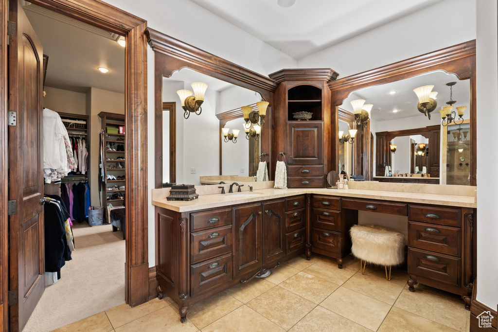 Bathroom with vanity, an inviting chandelier, a walk in closet, and tile patterned floors