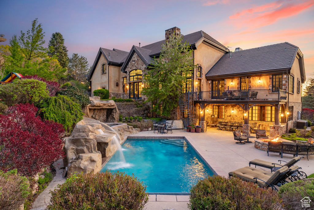 Pool at dusk with a patio, an outdoor pool, an outdoor fire pit, stairs, and central AC