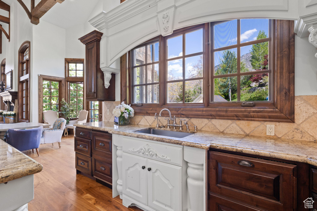 Kitchen featuring backsplash, light wood-style floors, white cabinetry, and a sink