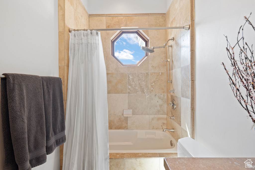 Bathroom with toilet and shower / bath combination with curtain