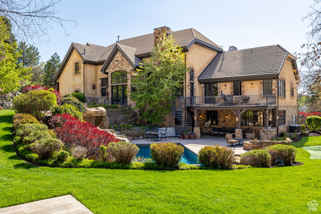 Back of property with a balcony, a patio area, stairway, and a lawn