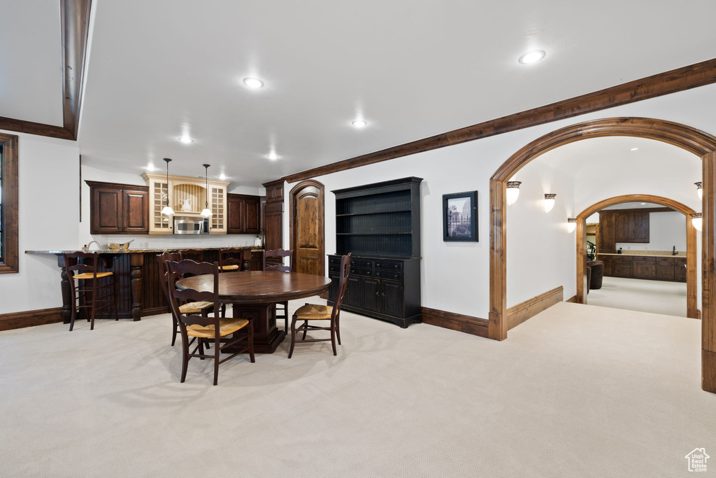 Dining space featuring light carpet, baseboards, arched walkways, and recessed lighting