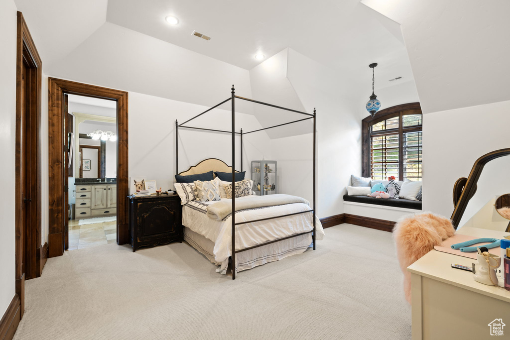 Bedroom featuring lofted ceiling, baseboards, ensuite bathroom, visible vents, and light colored carpet