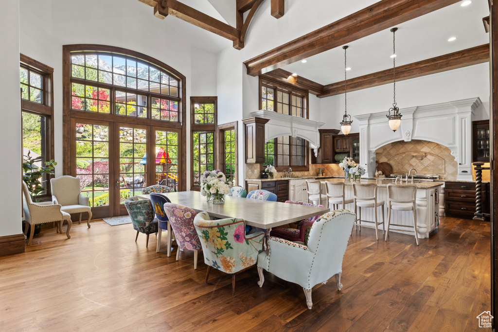 Dining area featuring a high ceiling, beamed ceiling, dark wood-style floors, and french doors