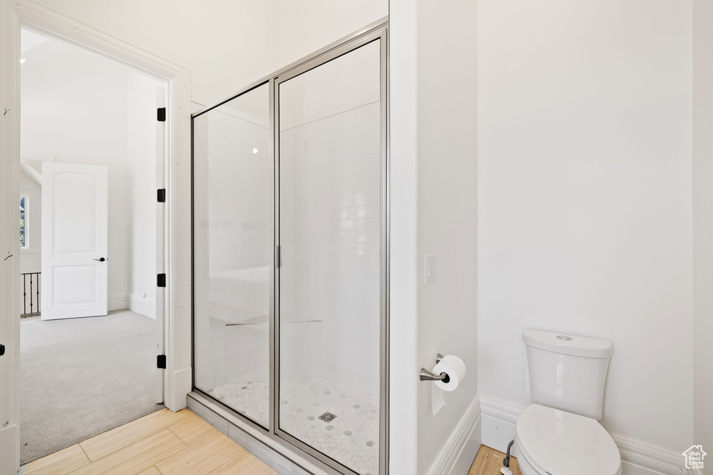 Full bath featuring toilet, baseboards, a shower stall, and wood finished floors