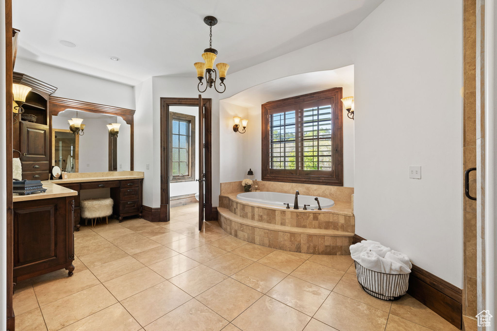 Bathroom featuring vanity, tile patterned floors, an inviting chandelier, baseboards, and a bath