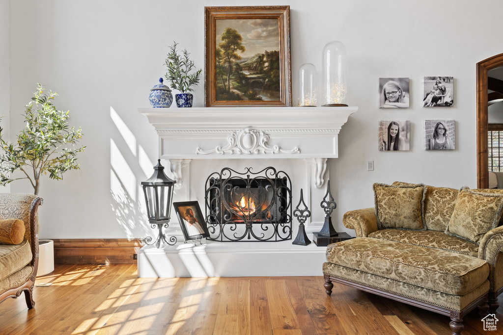 Sitting room with wood finished floors and a warm lit fireplace