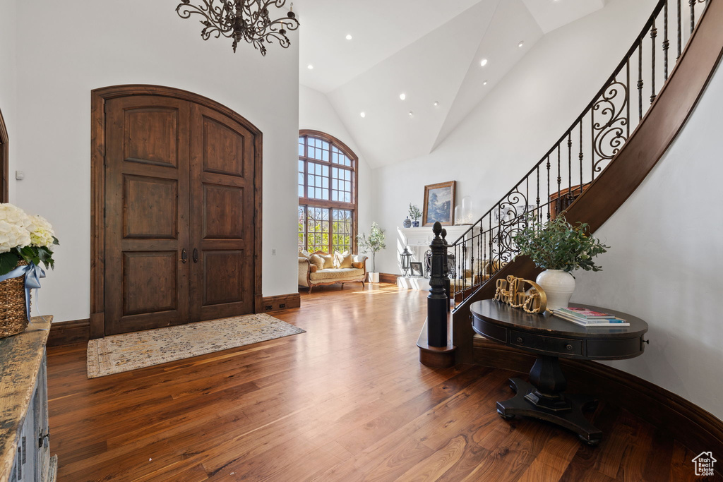 Foyer with hardwood / wood-style floors, high vaulted ceiling, recessed lighting, stairway, and baseboards