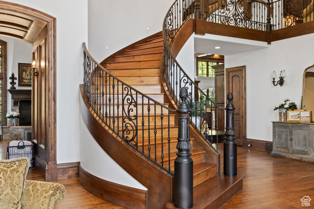Stairs with baseboards, hardwood / wood-style floors, and a towering ceiling