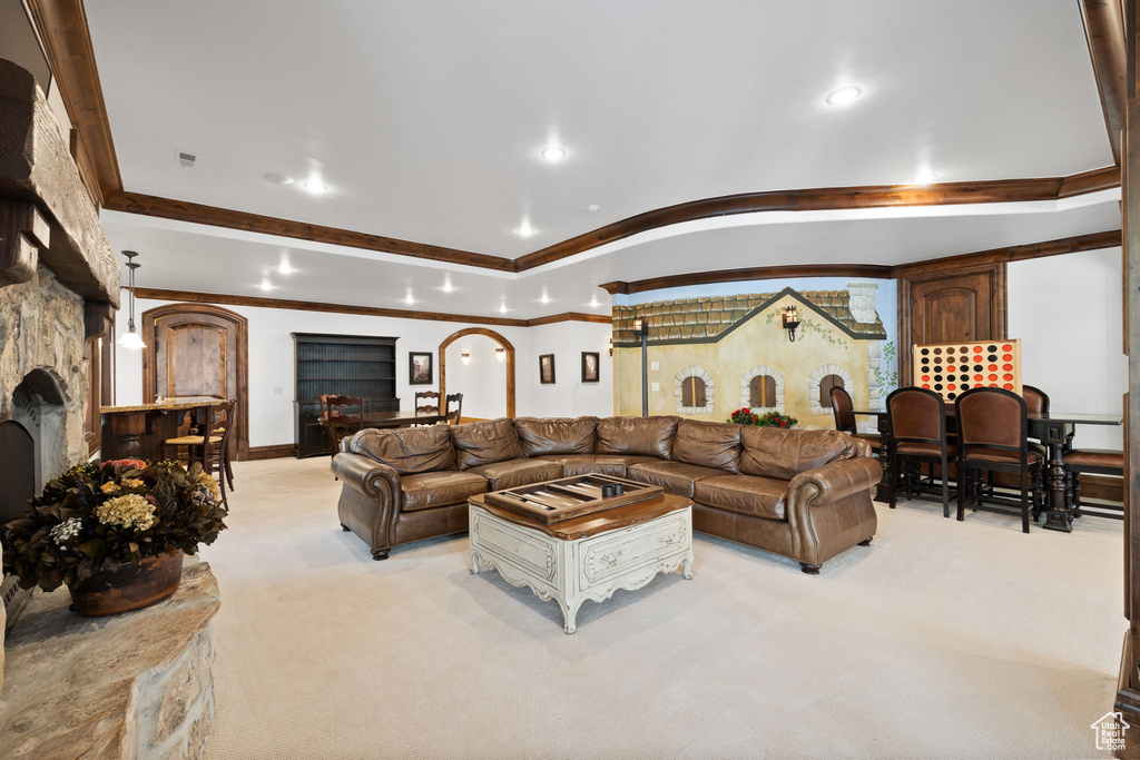 Living area with ornamental molding, light carpet, arched walkways, and recessed lighting