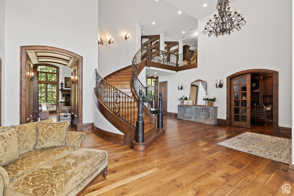 Entryway featuring stairs, hardwood / wood-style flooring, a towering ceiling, a fireplace, and arched walkways