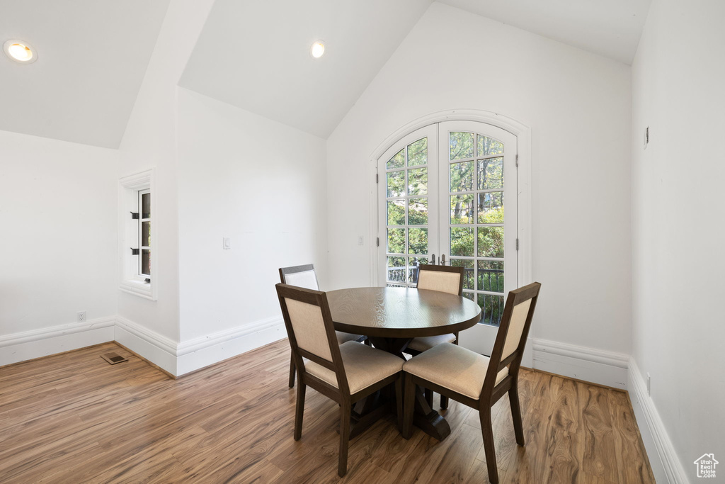 Dining space featuring baseboards, high vaulted ceiling, and wood finished floors